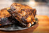 Close-up of browned asado-style ribs served on a stainless steel plate