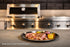 Sliced grilled steak with corn and vegetables, served in front of a Tucker R Class built-in BBQ