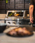 Whole roast chicken visible through the glass roasting hood of a Tucker R Class built-in BBQ
